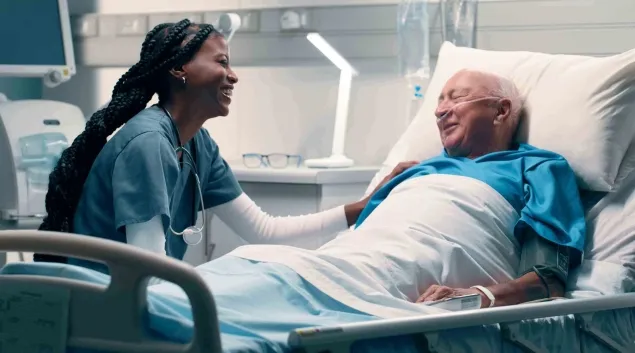 Healthcare worker talking to patient in hospital bed