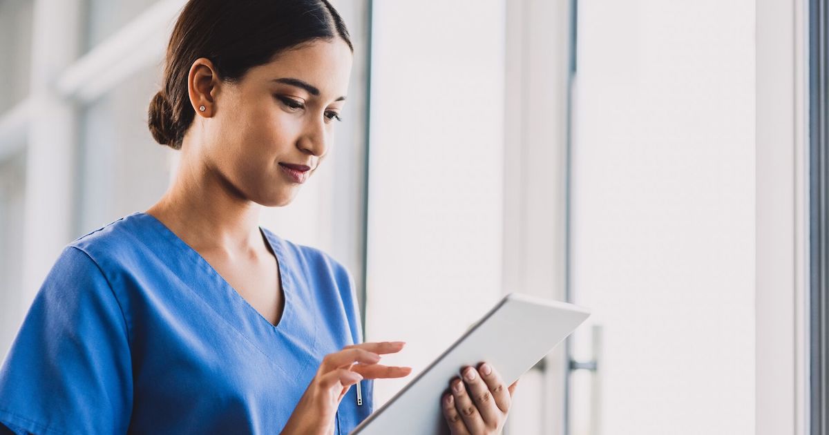 A nurse checking a patient's record on a digital tablet