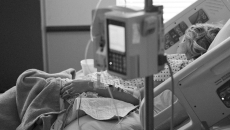 Woman asleep in hospital bed with IV in foreground