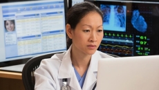 female doctor reviews patient data on multiple screens