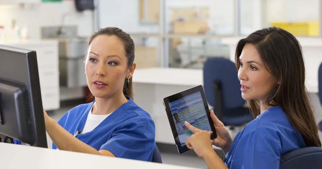 Two nurses confer about clinical documentation