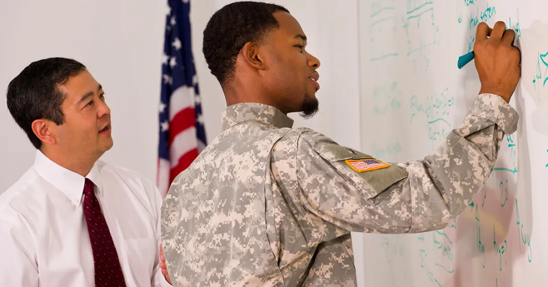 veteran draws on a whiteboard with a colleague