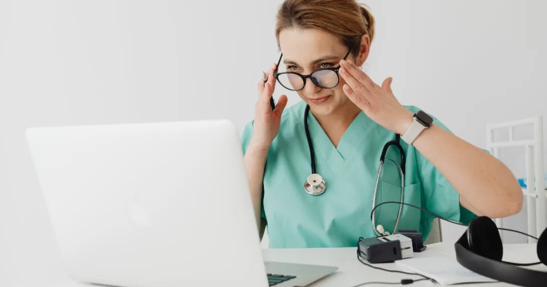 Doctor in scrubs setting up laptop for telehealth