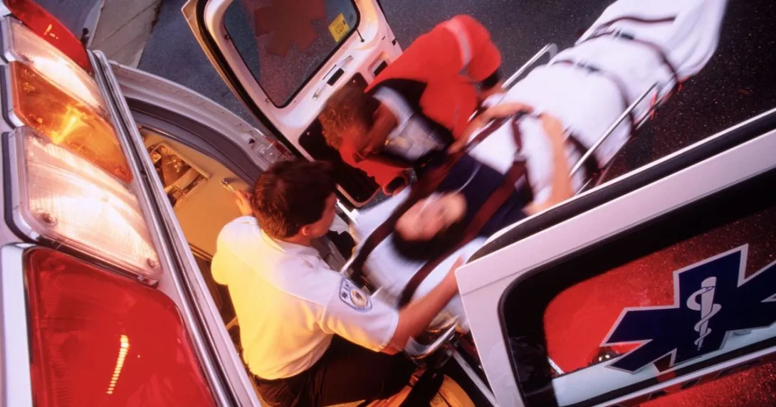 EMS technician comes out of an ambulance with patient on a stretcher