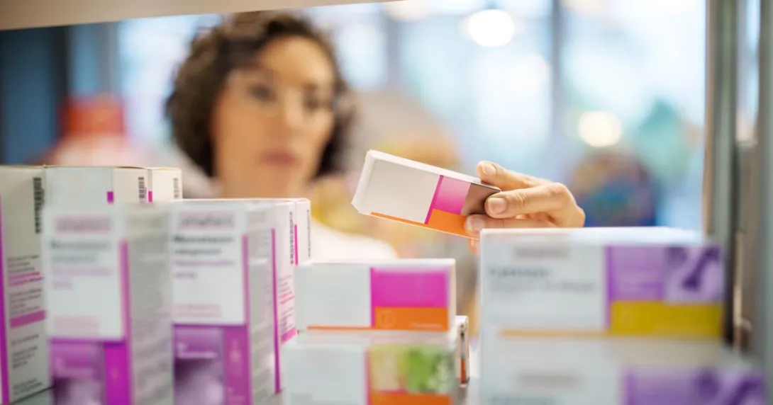Pharmacist holds and reads a prescription drug box