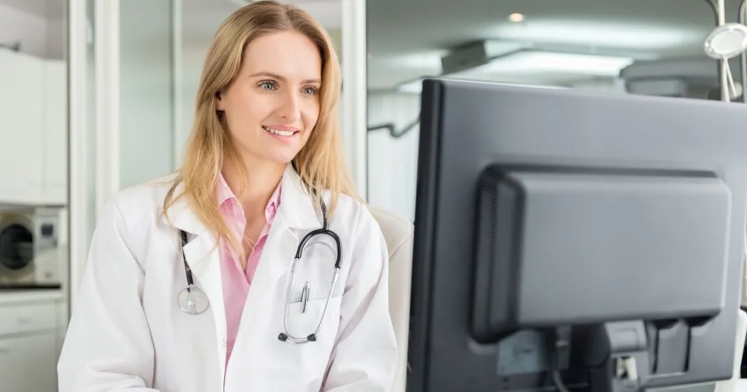 A doctor reviewing a patient's record on a desktop computer